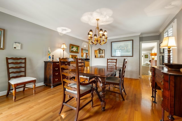 dining area featuring crown molding, a notable chandelier, and light hardwood / wood-style floors