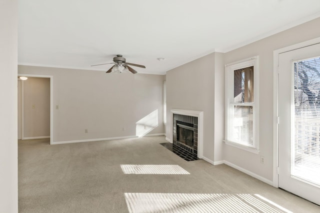 unfurnished living room featuring a tiled fireplace, ornamental molding, plenty of natural light, and light colored carpet