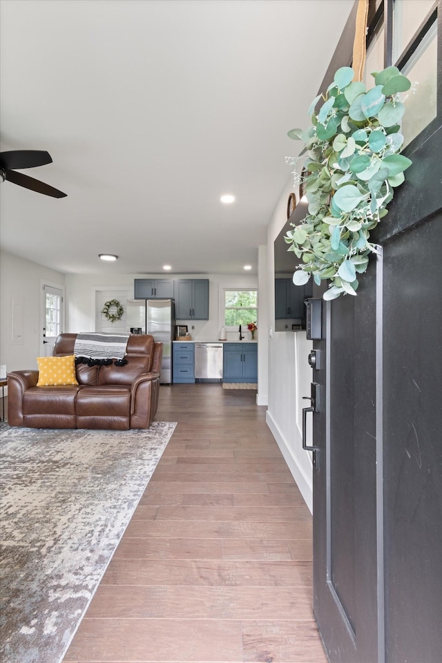 living room featuring ceiling fan, wood-type flooring, and a healthy amount of sunlight