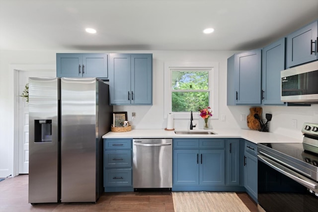 kitchen featuring blue cabinets, sink, wood-type flooring, and appliances with stainless steel finishes