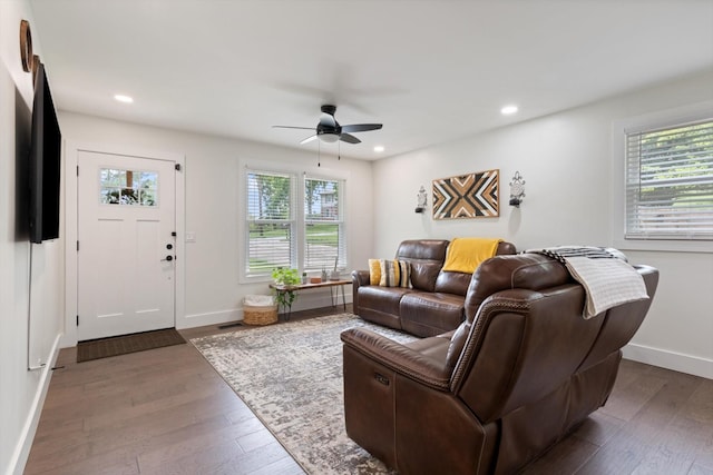 living room featuring dark wood-type flooring and ceiling fan