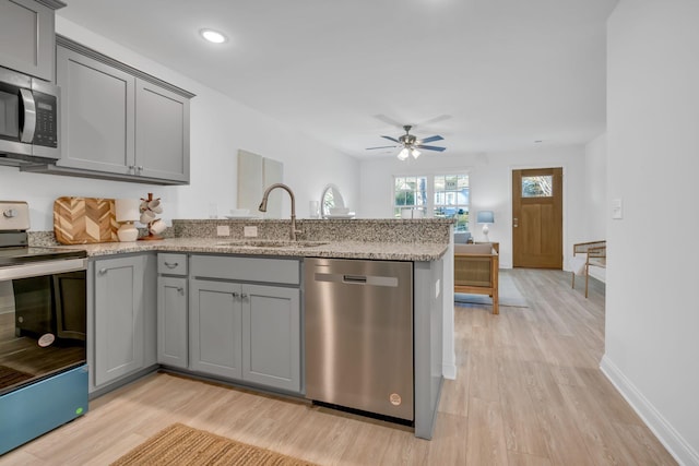 kitchen featuring sink, gray cabinetry, kitchen peninsula, stainless steel appliances, and light stone countertops