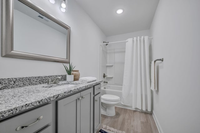 full bathroom featuring hardwood / wood-style flooring, vanity, shower / tub combo, and toilet