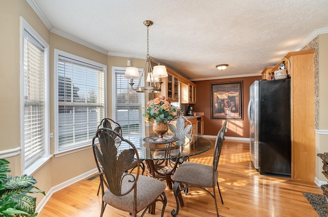 dining room featuring crown molding, light hardwood / wood-style flooring, and a textured ceiling