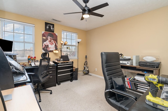 carpeted office space featuring ceiling fan and a textured ceiling