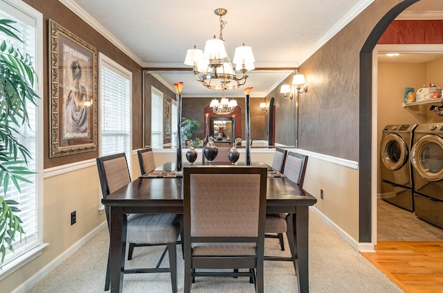 dining area featuring ornamental molding, a chandelier, washing machine and dryer, and light hardwood / wood-style flooring