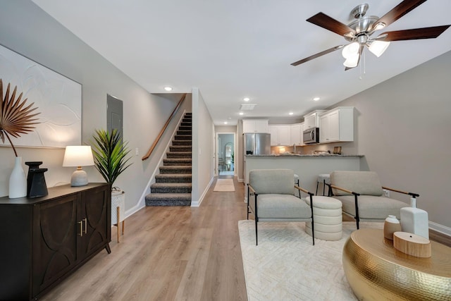 living room with ceiling fan and light wood-type flooring