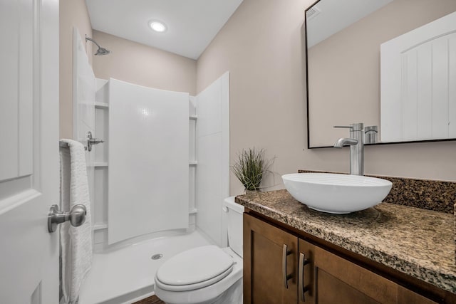 bathroom with vanity, a shower, and toilet