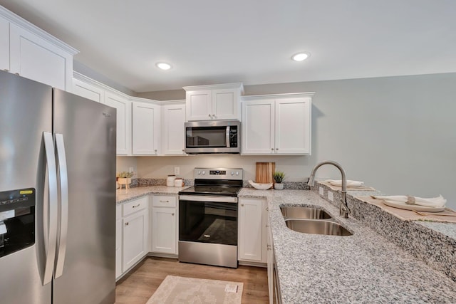 kitchen featuring appliances with stainless steel finishes, light stone countertops, sink, and white cabinets