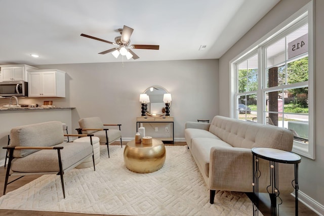 living room featuring ceiling fan and light hardwood / wood-style floors