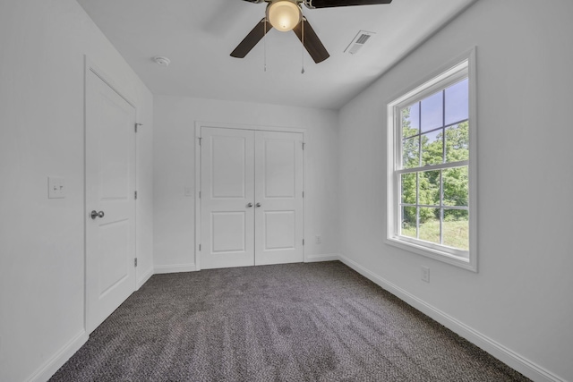 unfurnished bedroom featuring dark colored carpet, ceiling fan, and a closet