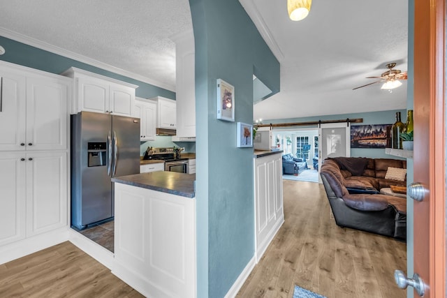 kitchen with light hardwood / wood-style flooring, white cabinetry, stainless steel appliances, ornamental molding, and a barn door