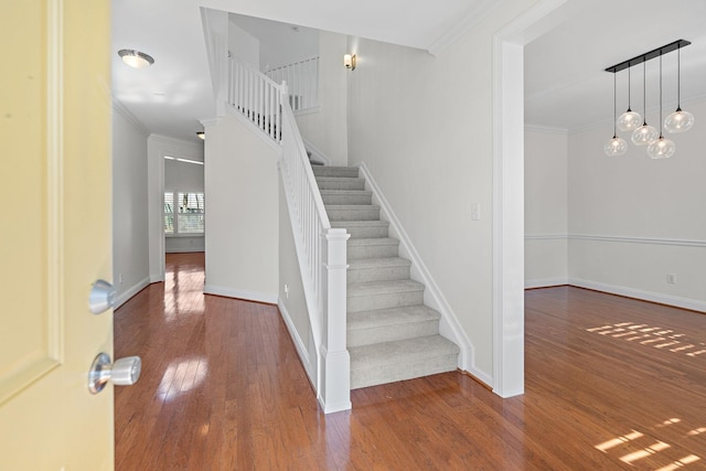 stairway with crown molding and hardwood / wood-style flooring