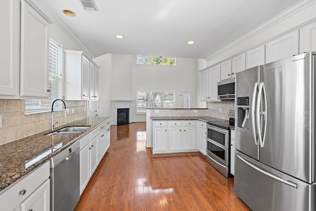 kitchen featuring sink, white cabinetry, tasteful backsplash, appliances with stainless steel finishes, and hardwood / wood-style flooring