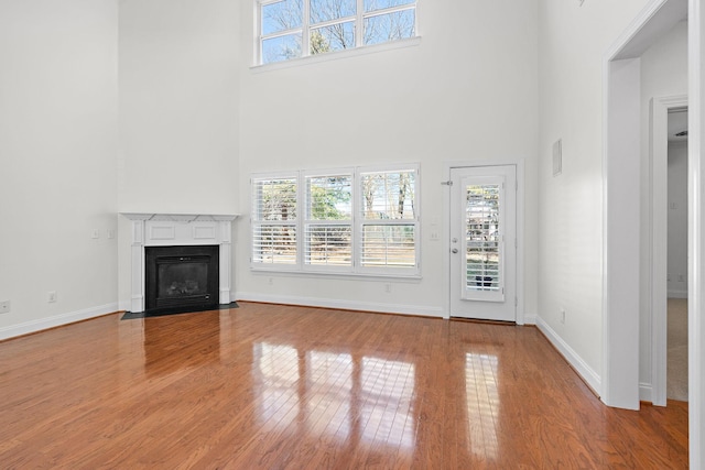 unfurnished living room with a high ceiling and light hardwood / wood-style floors