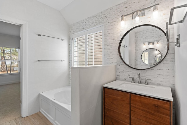 bathroom with a bathing tub, vanity, lofted ceiling, and hardwood / wood-style flooring