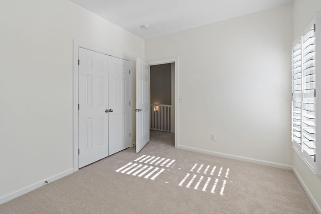 unfurnished bedroom with light colored carpet and a closet