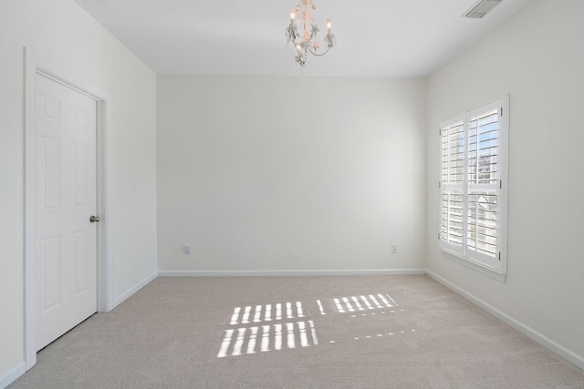 spare room with light carpet and a notable chandelier