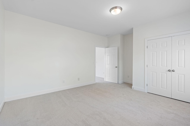 unfurnished bedroom featuring light colored carpet and a closet