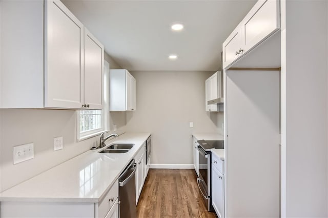 kitchen featuring appliances with stainless steel finishes, sink, hardwood / wood-style floors, and white cabinets