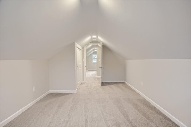 additional living space featuring lofted ceiling and light colored carpet