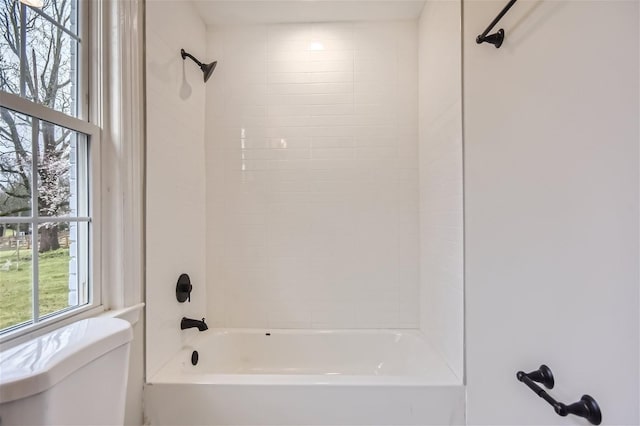 bathroom with toilet and tiled shower / bath combo