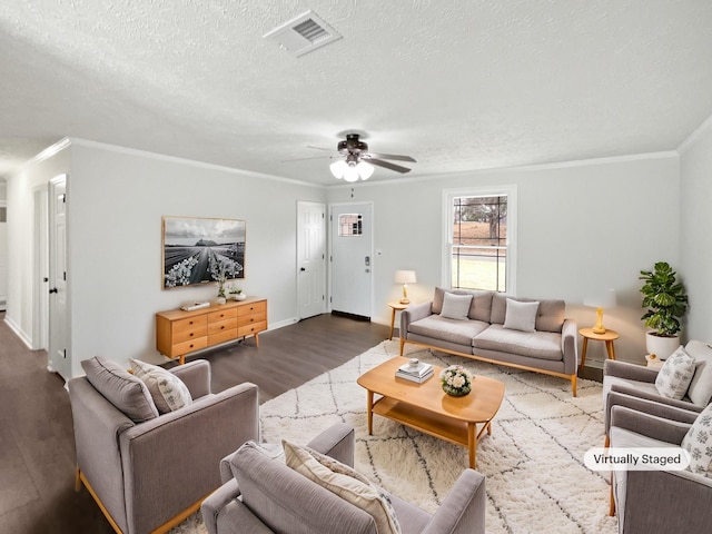 living room with dark wood-type flooring, ceiling fan, ornamental molding, and a textured ceiling