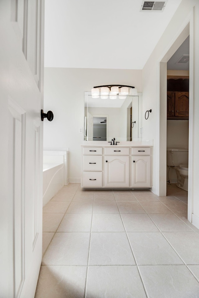 bathroom with tile patterned flooring, vanity, a bathing tub, and toilet