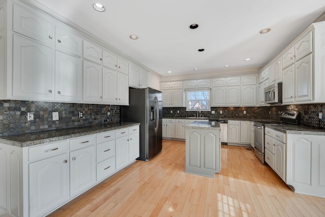 kitchen featuring a kitchen island, white cabinetry, appliances with stainless steel finishes, and dark stone countertops