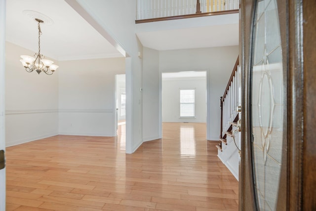 foyer entrance featuring ornamental molding, a chandelier, and light hardwood / wood-style flooring