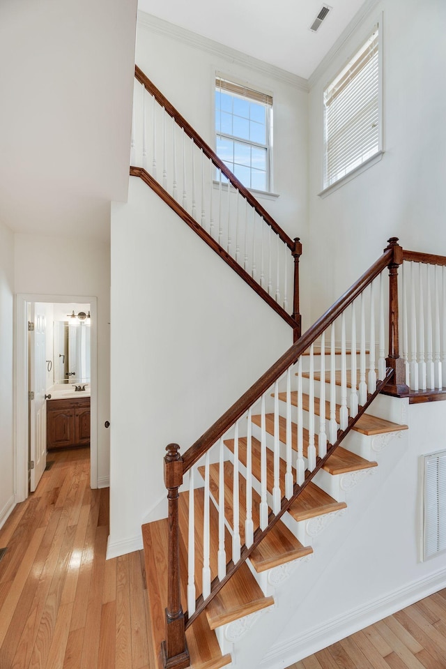 stairs featuring crown molding and hardwood / wood-style floors