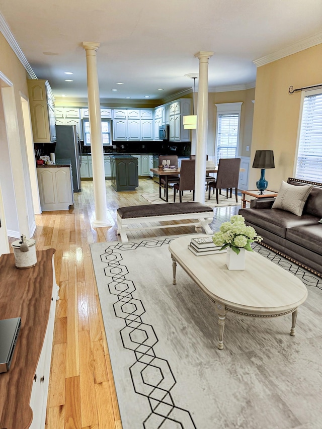 living room featuring ornate columns, crown molding, and light wood-type flooring