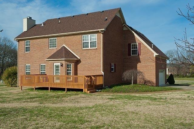 back of property featuring a wooden deck and a lawn