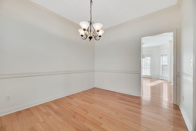 spare room featuring crown molding, an inviting chandelier, and light hardwood / wood-style flooring