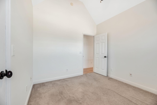 carpeted spare room with high vaulted ceiling