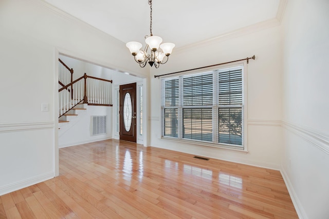 foyer with a notable chandelier, light hardwood / wood-style flooring, and ornamental molding