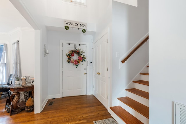 foyer with crown molding and dark wood-type flooring