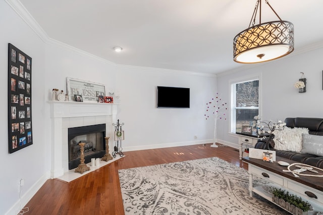 living room featuring crown molding, a tiled fireplace, and hardwood / wood-style floors