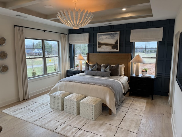 bedroom with a tray ceiling, light hardwood / wood-style flooring, and a chandelier