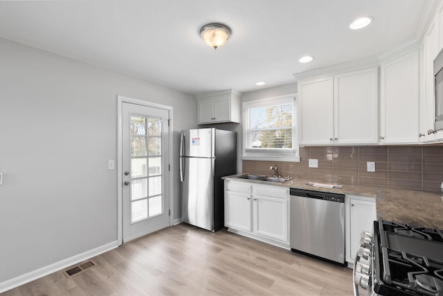 kitchen featuring sink, white cabinetry, stainless steel appliances, light stone countertops, and backsplash