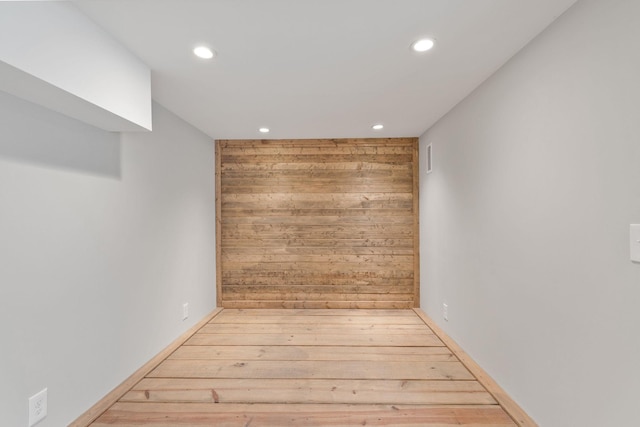 unfurnished room featuring light wood-type flooring and wood walls