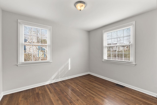 spare room with plenty of natural light and dark wood-type flooring