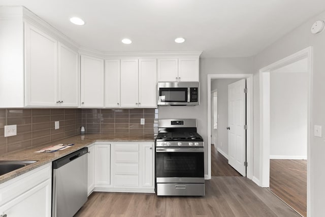 kitchen featuring white cabinetry, light stone countertops, tasteful backsplash, and stainless steel appliances