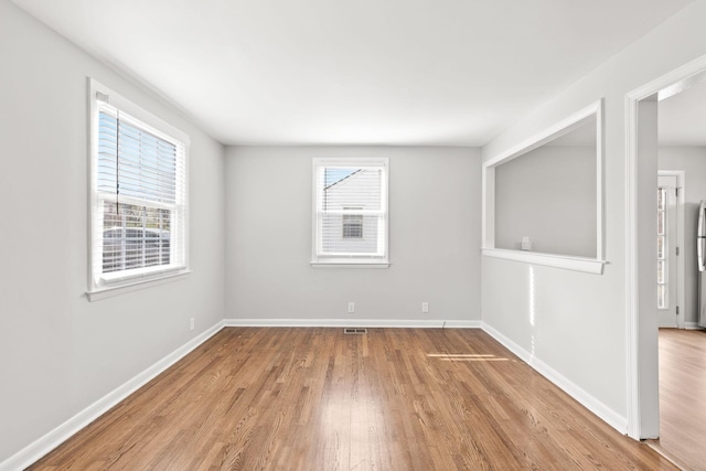 spare room featuring a healthy amount of sunlight and light hardwood / wood-style floors