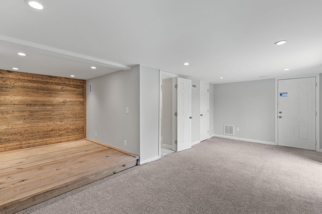 carpeted empty room with wood walls