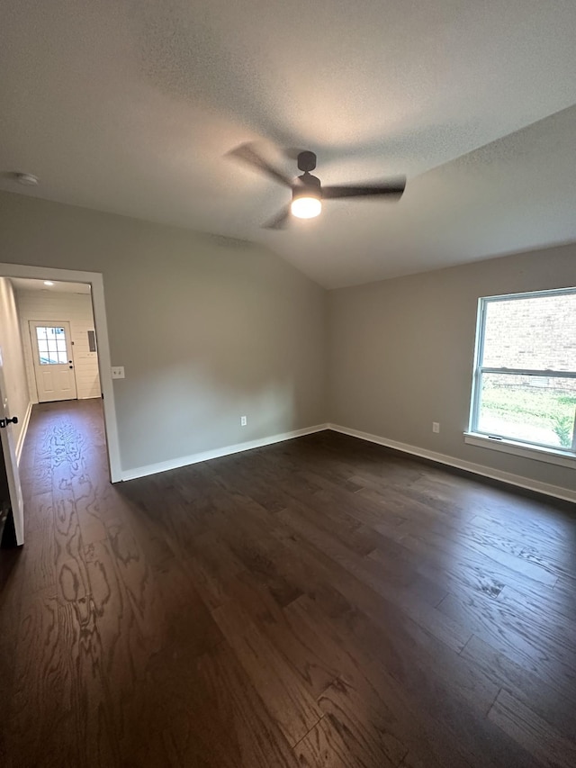 empty room featuring ceiling fan, lofted ceiling, dark wood-type flooring, and a textured ceiling