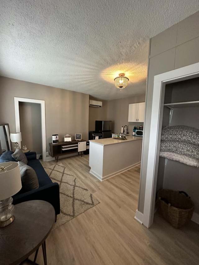 living room featuring a textured ceiling, a wall unit AC, and light hardwood / wood-style floors