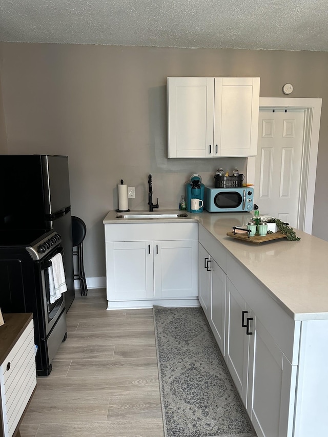 kitchen with sink, white cabinets, light hardwood / wood-style floors, stainless steel appliances, and a textured ceiling