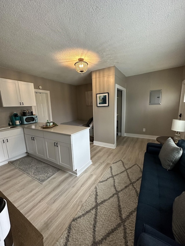 kitchen featuring white cabinetry, light hardwood / wood-style flooring, and a textured ceiling