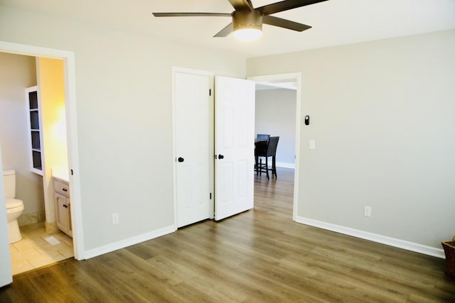 unfurnished bedroom featuring hardwood / wood-style flooring, ensuite bath, and ceiling fan